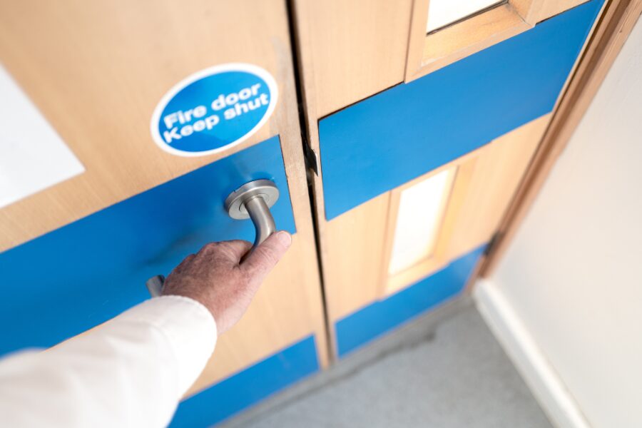 Blog Featured Header – Fire Door Ironmongery Regulations Man opening fire door with handle